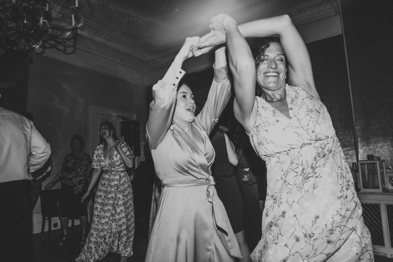Black and white photo of two woman at a wedding dancing into the night!